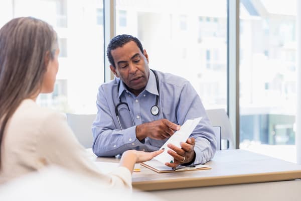 Doctor consulting with their patient holding notes.