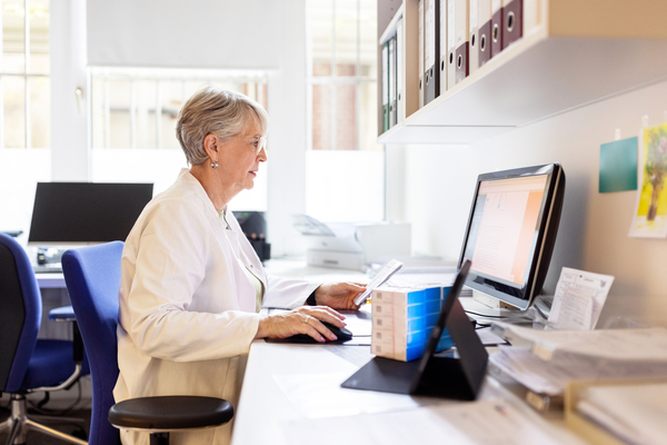 Pharmacist getting support through their phone and computer.