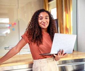 woman smiling holding a laptop